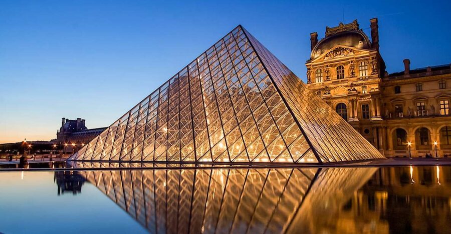 The glass pyramid lit at dusk in the courtyard of the Louvre